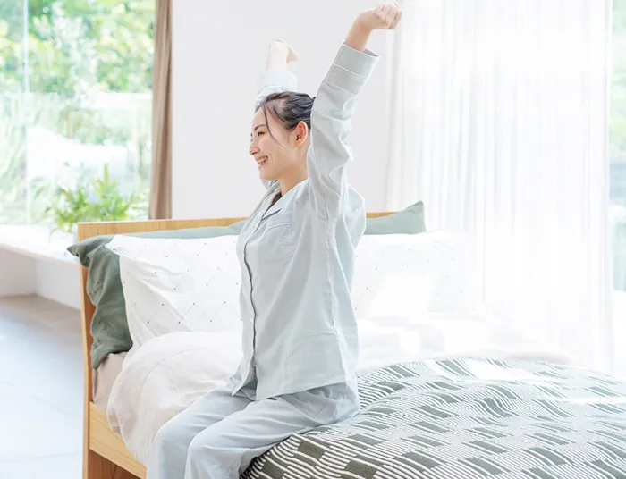 ベッドから起きあがろうとする女性